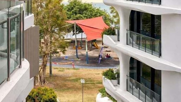 Een modern gebouw met meerdere balkons met uitzicht op een strand.