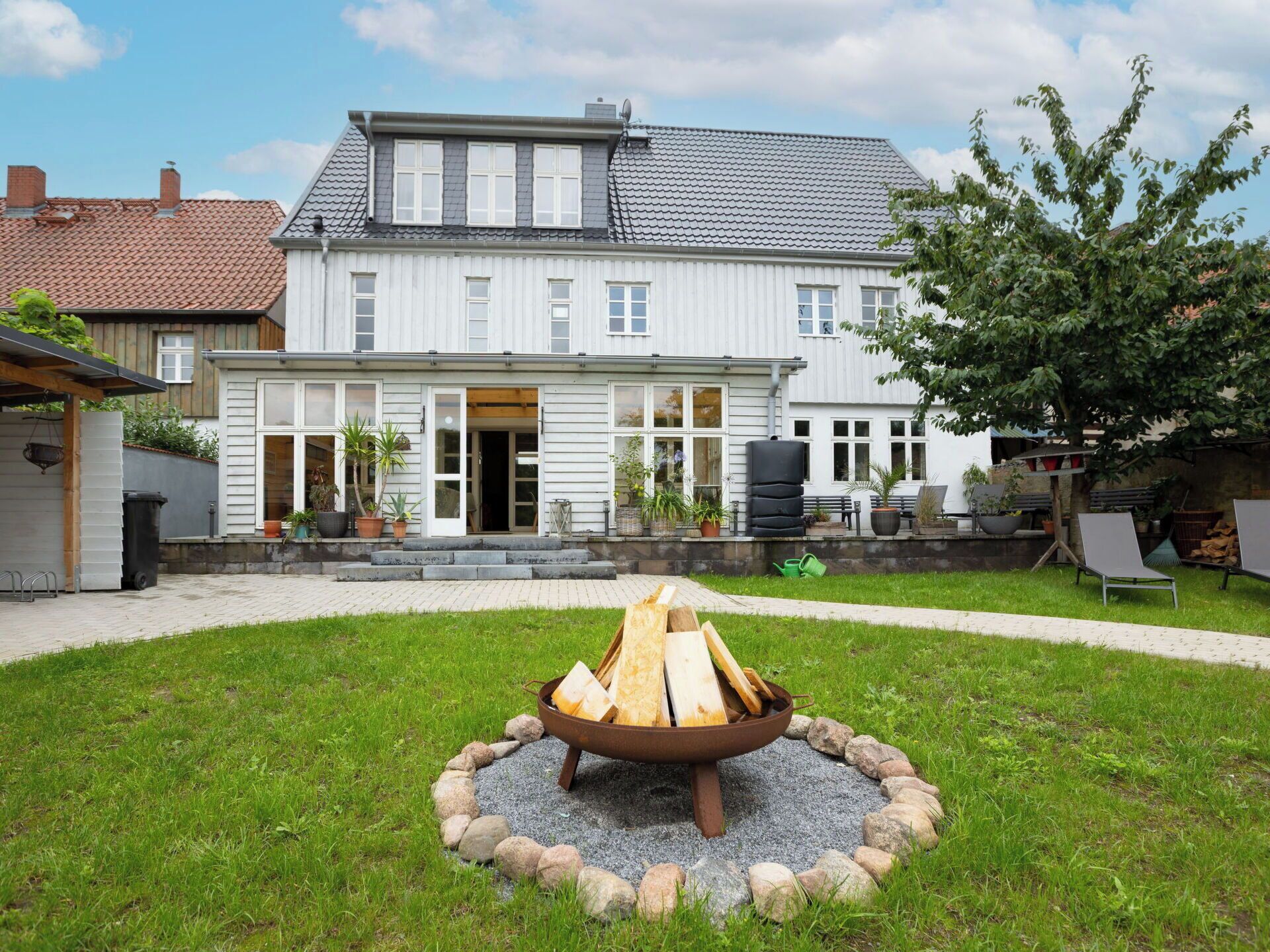 A house with a fire pit in the yard surrounded by rocks.