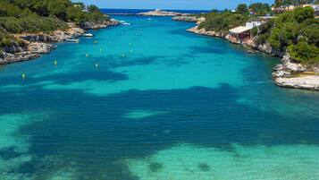 A coastal area with clear turquoise waters, rocky shores, and greenery.