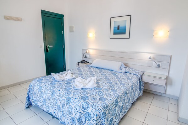 A neatly made bed with a blue and white patterned bedspread and two white towels.