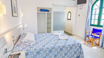 A hotel room with a bed, a desk, a chair, a wardrobe, and a TV.