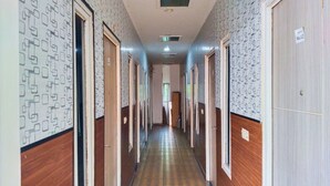Un long couloir aux murs ornés de motifs et aux portes en bois, qui mène à plusieurs pièces.
