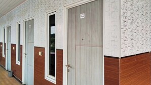 Un couloir bordé de portes, chacune étant surmontée d’une plaque indiquant le numéro de la pièce.