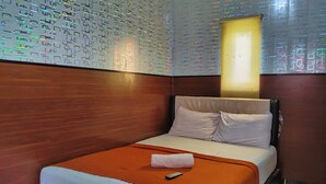 Une chambre d’hôtel avec un lit soigneusement fait, une télécommande posée sur le lit et un mur orné d’un motif géométrique.
