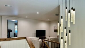 Ein modernes Wohnzimmer mit einem Flachbildfernseher, einer Couch und einer Treppe mit Holelllauf.