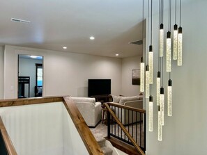 Ein modernes Wohnzimmer mit einem Flachbildfernseher, einer Couch und einer Treppe mit Holelllauf.