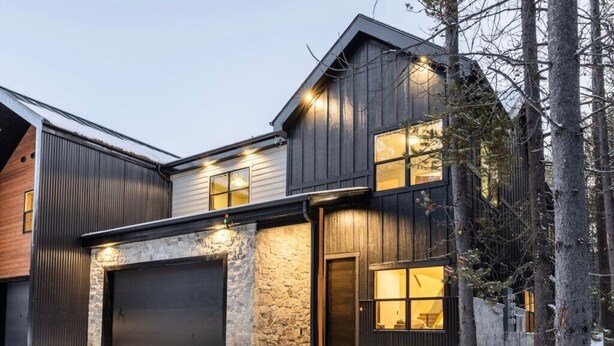 Ein modernes, zweistöckiges Haus mit Garage, Stein Fundament und Holzfassade.