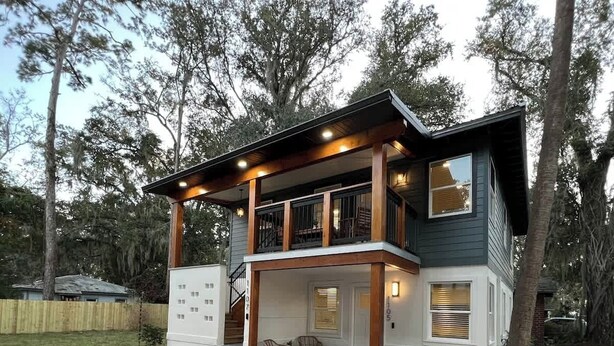 A two-story house with a covered porch, a staircase leading to the upper level, and a small outdoor seating area. - Walk to UF/Stadium | Near Shands/Downtown (NEW!) (Gainesville)