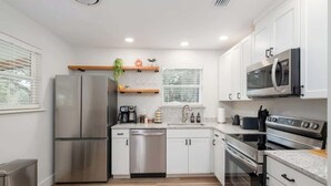 A modern kitchen with stainless steel appliances, white cabinetry, and a wooden floor. - Walk to UF/Stadium | Near Shands/Downtown (NEW!) (Gainesville)