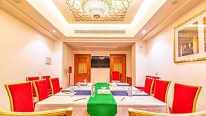 Une salle de conférence avec une longue table, des chaises rouges et un chemin de table vert.