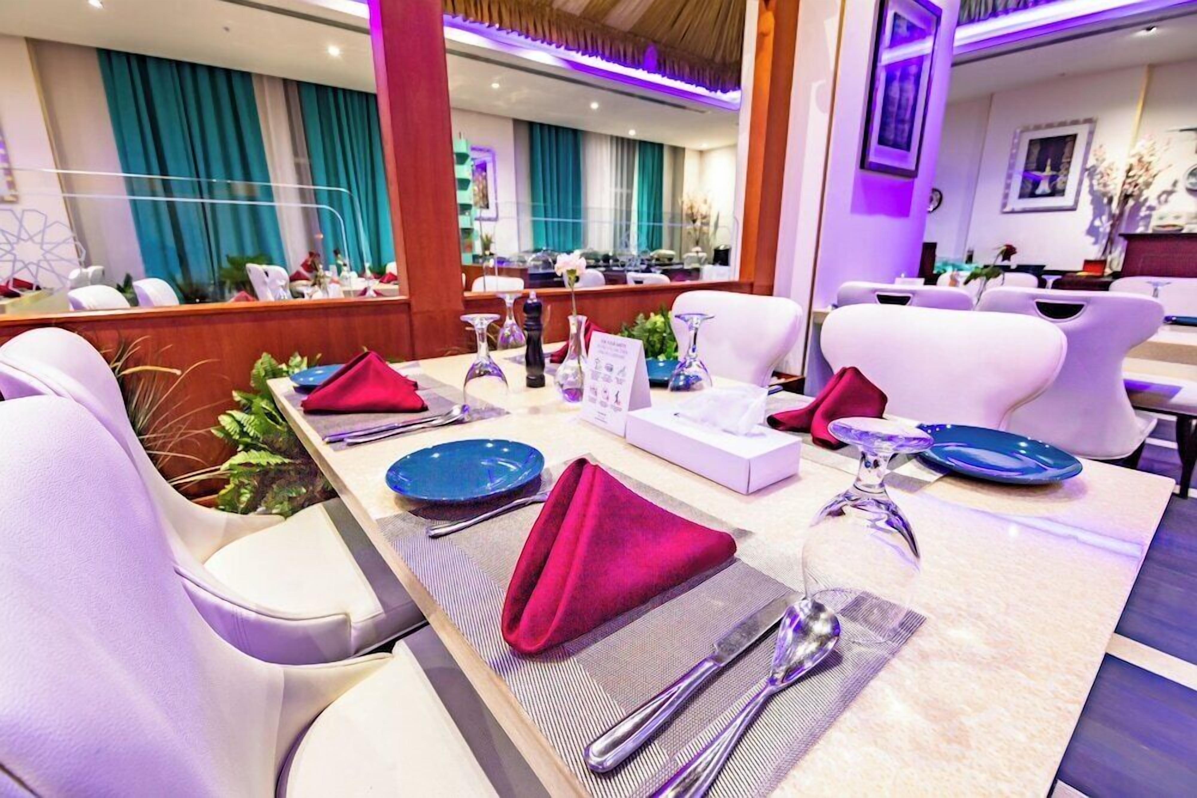Un restaurante con sillas blancas, una mesa de mármol y vista al salón comedor.