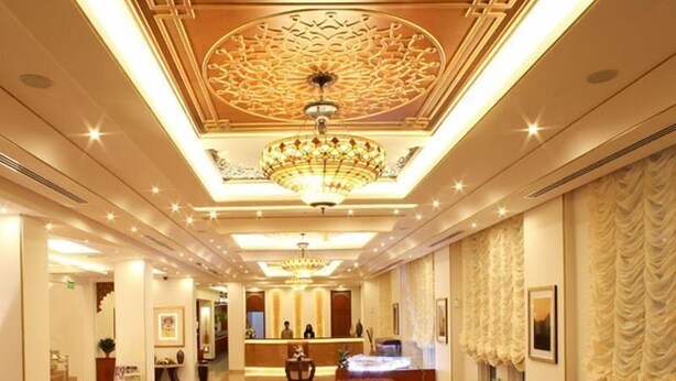 Un hall d’hôtel comprenant un comptoir d’accueil, un espace salon et un plafond décoratif.