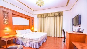 Une chambre d’hôtel équipée d’un lit, d’un bureau, d’une chaise et d’un téléviseur.