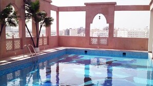Une piscine à l’eau d’un bleu cristallin, entourée d’une terrasse carrelée et de palmiers.