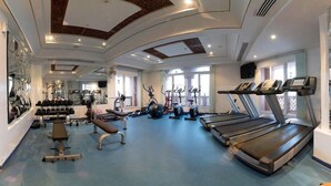 Une salle de sport équipée de tapis de course, d’appareils de musculation et d’haltères.