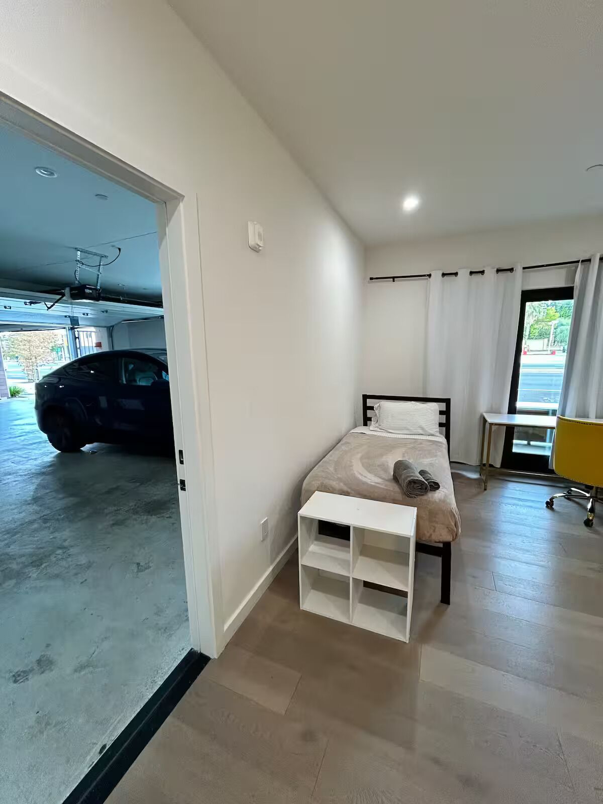 Un dormitorio con cama, escritorio y vista a un estacionamiento.