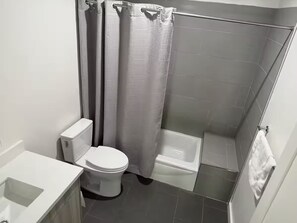 Ett badrum med toalett, dusch och badkar.