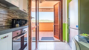 Eine Küche mit Blick auf einen Balkon, inklusive Kühlschrank und Mikrowelle.