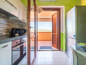 A modern kitchen with a sliding glass door leading to a balcony. - Apartment Parigi by Interhome (Villasimius)