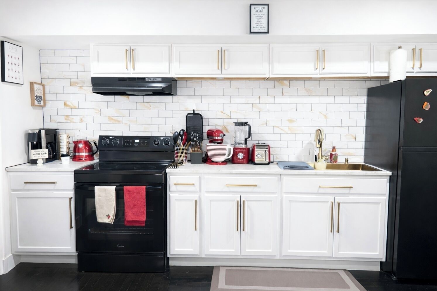 Une cuisine moderne avec des meubles blancs, une cuisinière noire et divers appareils électroménagers.
