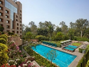 Ein Pool, umgeben von üppiger Vegetation und einem mehrstöckigen Gebäude.