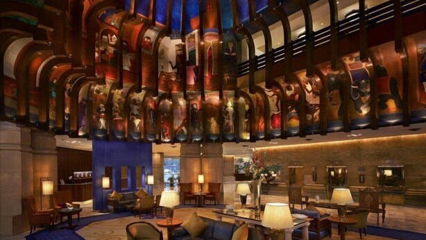 A lobby with a central seating area, a reception desk, and a wall with a series of framed artworks. - ITC Maurya, a Luxury Collection Hotel (New Delhi)