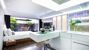 A modern kitchen with a white countertop, a dining area with a table and chairs, and a bed with a view to the outside. - V Wanchai Serviced Apartments (Hong Kong Island)