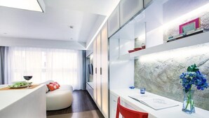 A modern hotel room with a white desk, a red chair, a sofa, and a large window with sheer curtains. - V Wanchai Serviced Apartments (Hong Kong Island)