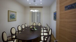A conference room with a long table, chairs, a chandelier, and a sign indicating it's a conference room. - Aria Hotel (Mahala)