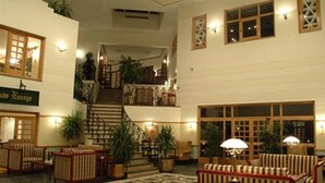A spacious lobby with a central staircase, multiple seating areas, and a patterned floor.