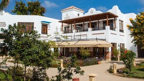 A white building with a balcony and outdoor seating area.