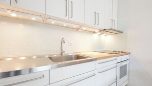 Une cuisine moderne avec des armoires blanches, des appareils en acier inoxydable et un éclairage sous les armoires.