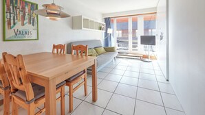 Un espace repas moderne avec une table et des chaises en bois, un canapé et un téléviseur.