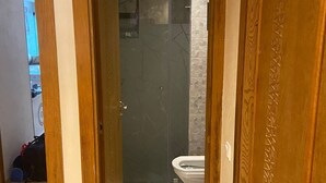 Ein Badezimmer mit Dusche, Toilette und Fliesenboden.