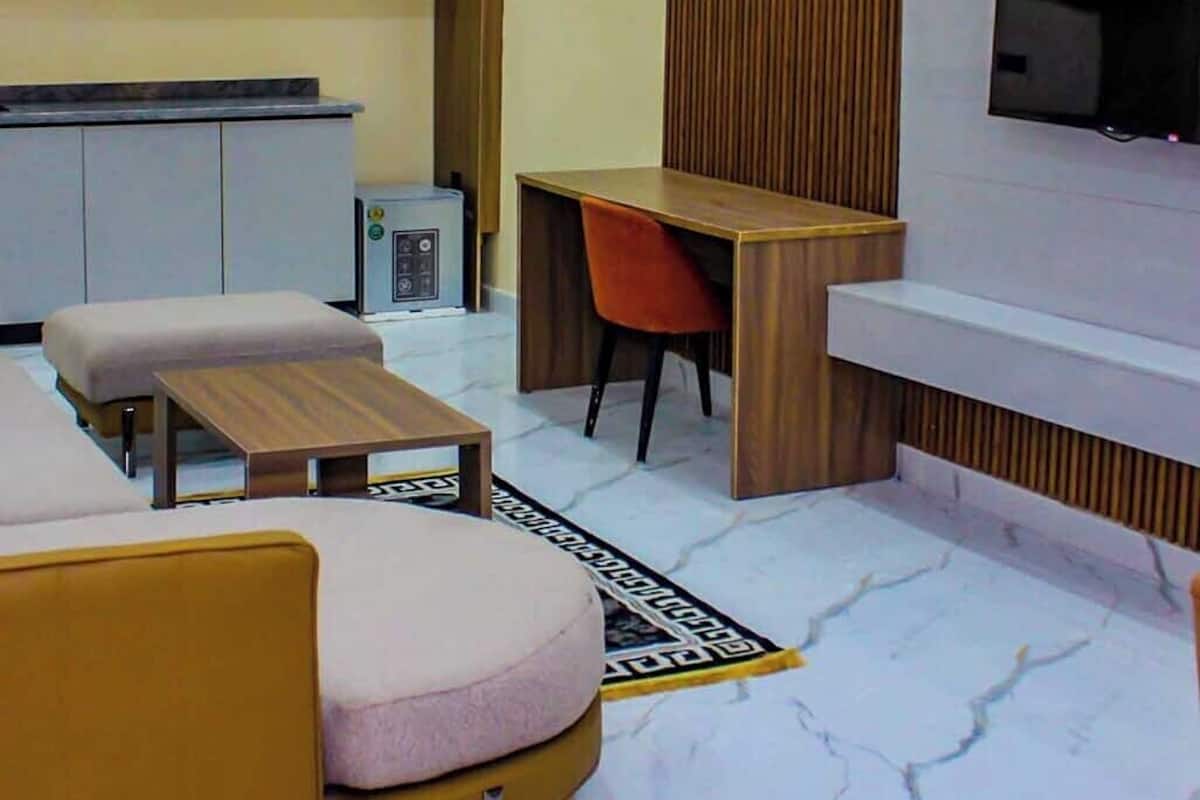 A modern living room with a sofa, a coffee table, a TV mounted on the wall, and a wooden desk with a chair.