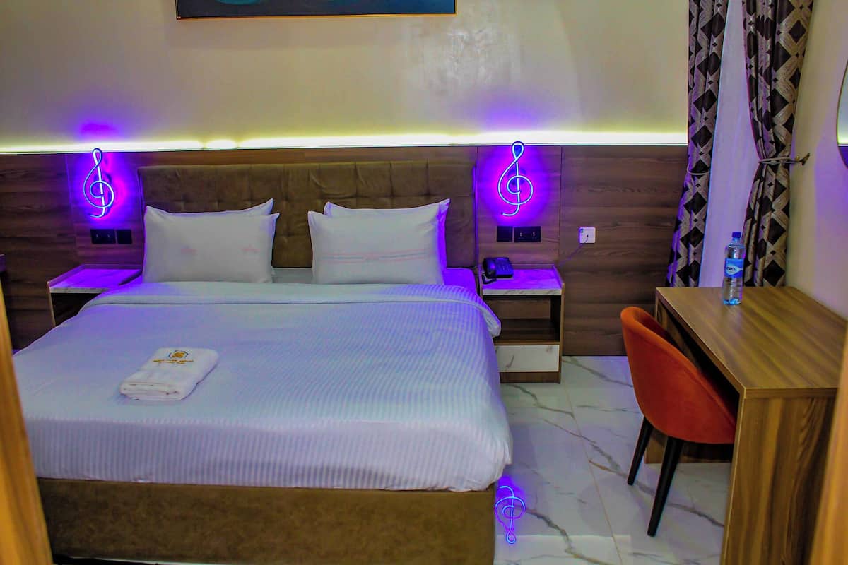 A hotel room with a large bed, two nightstands, a desk, and a chair.