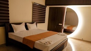 Un letto rifatto con una coperta marrone, cuscini bianchi e un asciugamano bianco piegato sopra.