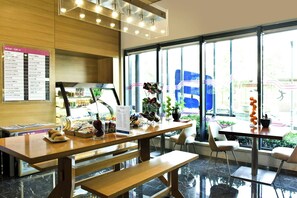 A modern cafe interior with a wooden counter, seating area, and large windows offering a view of the street. - Aloft Haidian Hotel Beijing (Beijing)