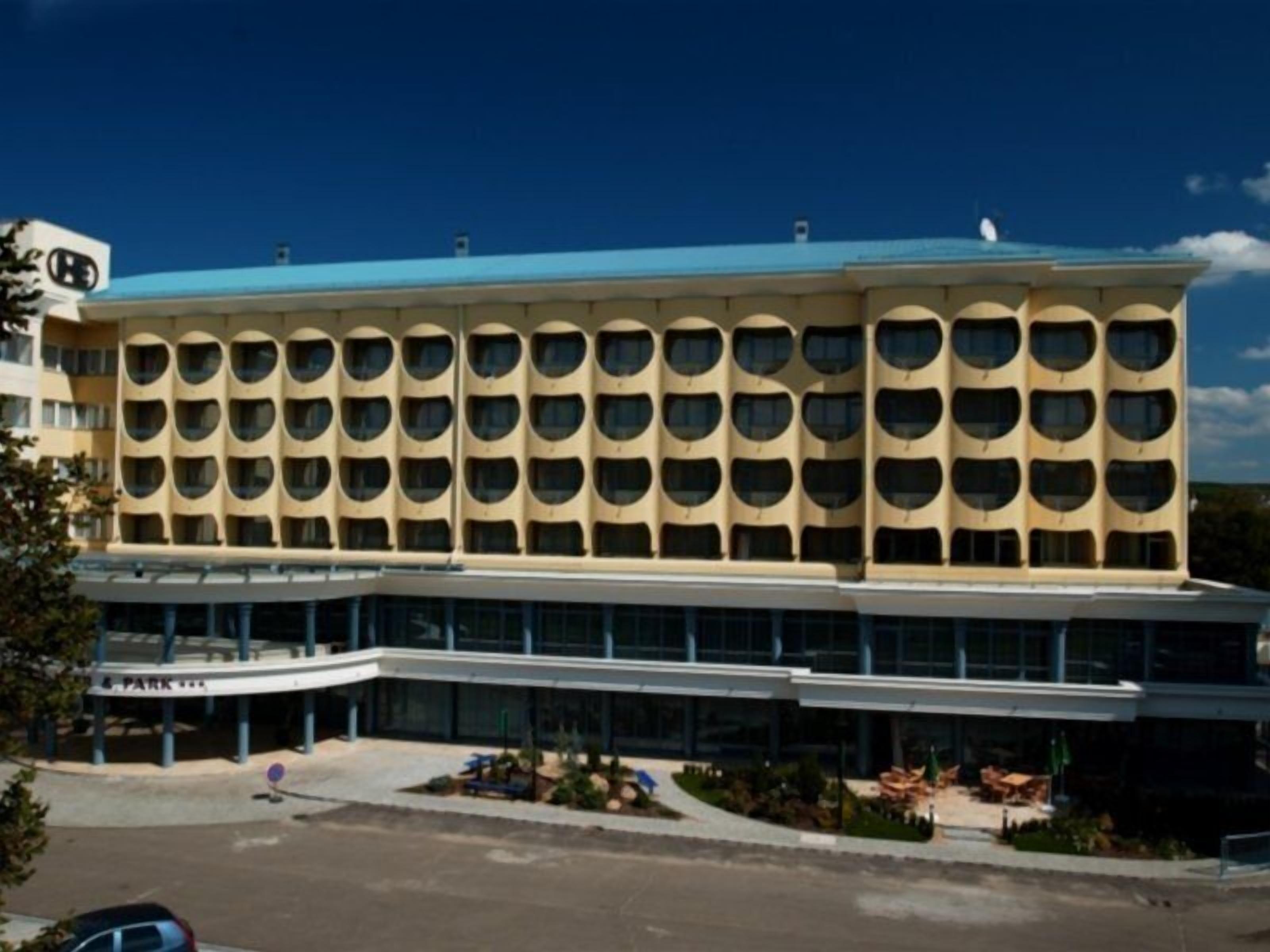 A multi-story hotel with a distinctive facade featuring a series of circular windows and a flat roof.