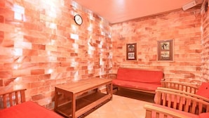 A room with a brick wall, a wooden table, a red sofa, and two wooden chairs. - Eger Park (Eger)