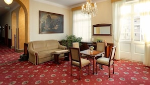 A room with a sofa, dining table, chairs, a chandelier, a painting, and a window with curtains. - Eger Park (Eger)