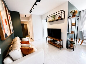 Una sala de estar moderna con un sofá, televisión y estanterías decorativas.