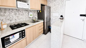 Een moderne keuken met houten kastjes, een roestvrijstalen koelkast, een magnetron en een gasfornuis.