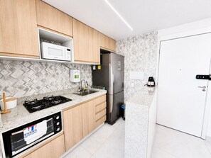 A modern kitchen with wooden cabinets, a stainless steel refrigerator, a microwave, and a gas stove. - Hosts BR - Viva Praia do Futuro (Fortaleza)