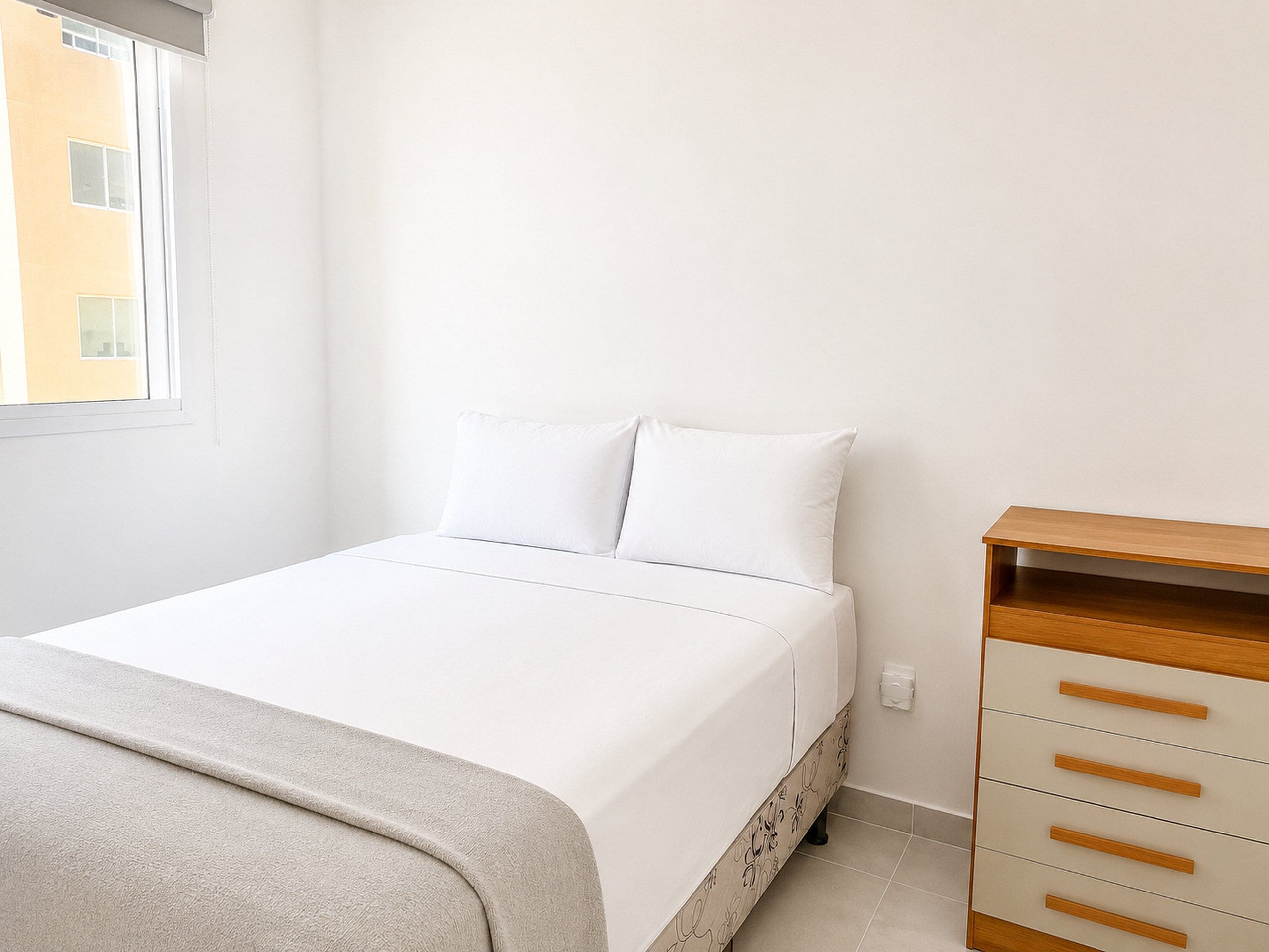 A bedroom with a bed, a dresser, and a window.