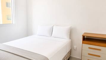 A bedroom with a bed, a dresser, and a window.