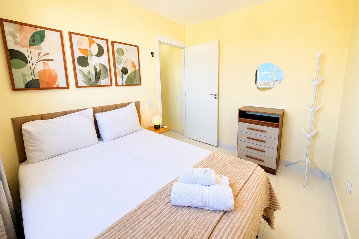 Una camera d'albergo con un letto, un comodino con una lampada, un armadio e tre quadri appesi al muro.