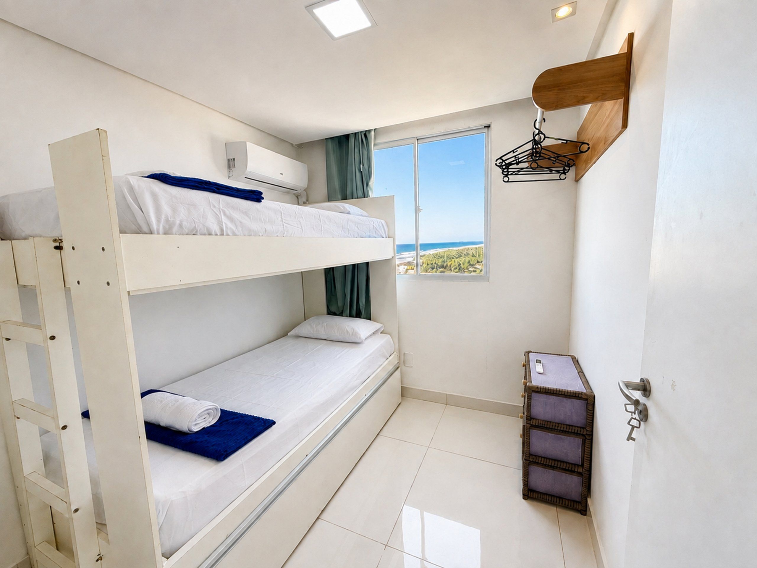 A bunk bed room with a window, a wall-mounted shelf, and a small table.