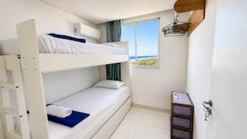 A bunk bed room with a window, a wall-mounted shelf, and a small table.