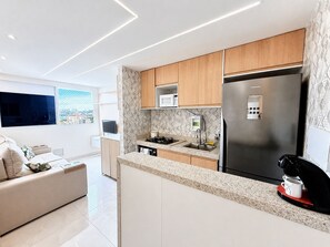 Una cocina moderna con microondas integrado, un refrigerador de acero inoxidable y una cafetera.
